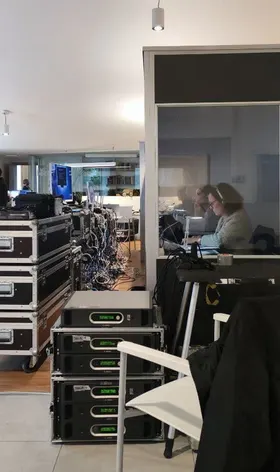 An interpreter working in her booth, next to the stacks of audio equipment.